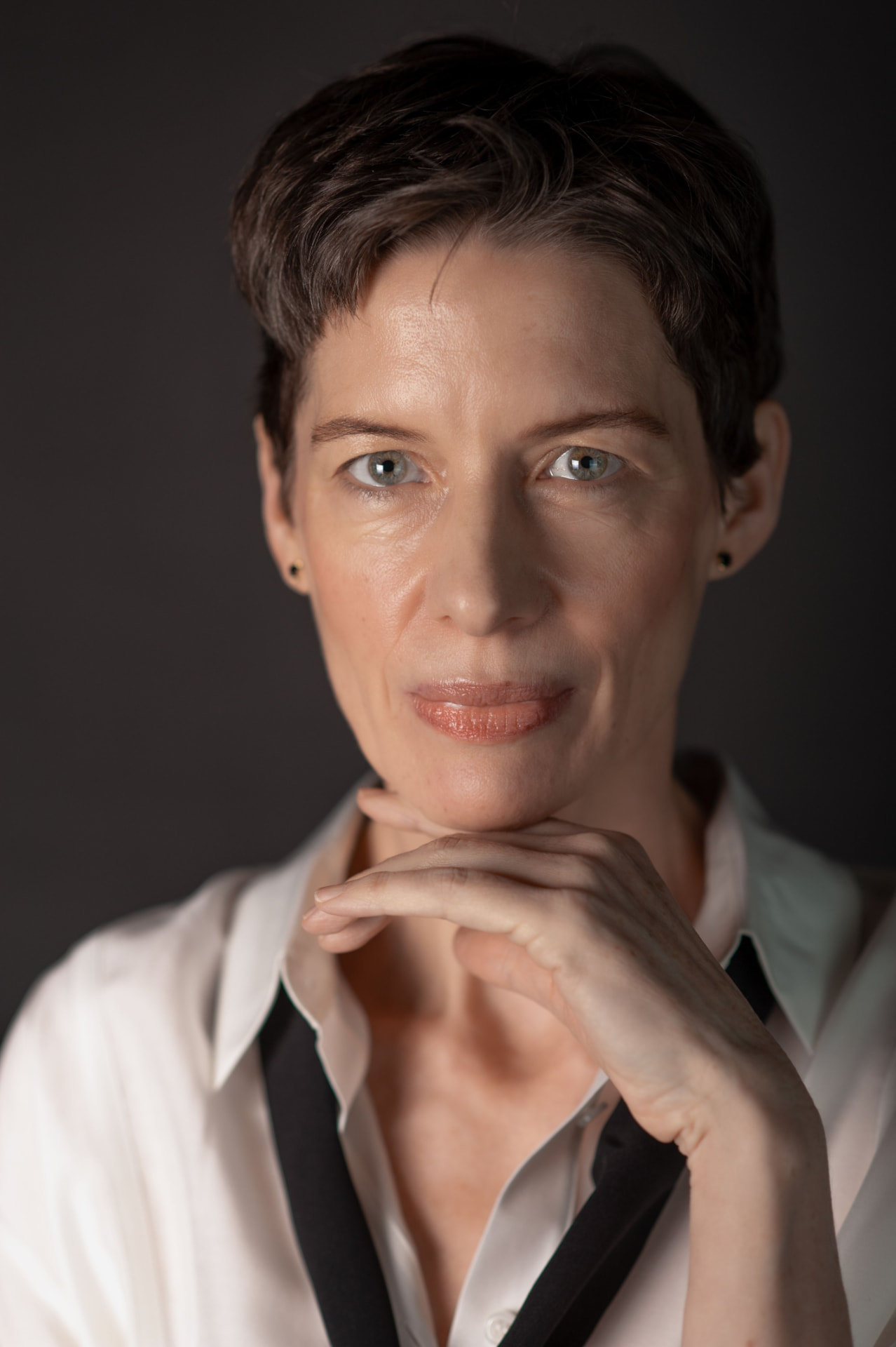 Portrait of a woman with short dark hair resting her chin on her hand